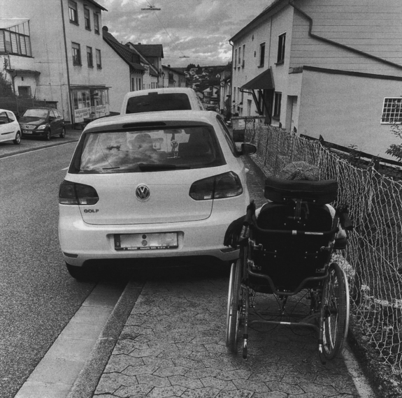 Weißes Auto, das auf dem Bürgersteig parkt, Rollstuhlfahrer rechts kommt nicht daran vorbei